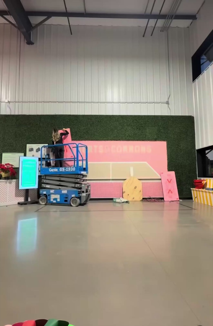 A pink custom event build being installed in a large white venue